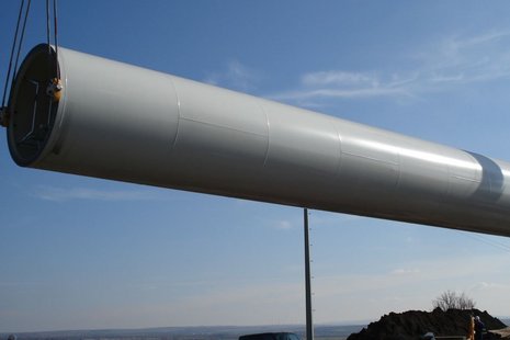 Der Mast einer Windkraftanlage wird vom Boden angehoben.