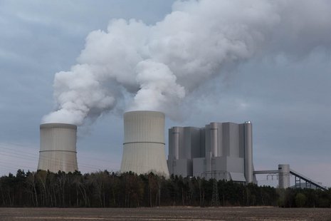 Aktives Kohlekraftwerk mit zwei Schornsteinen aus denen Rauch emporsteigt.